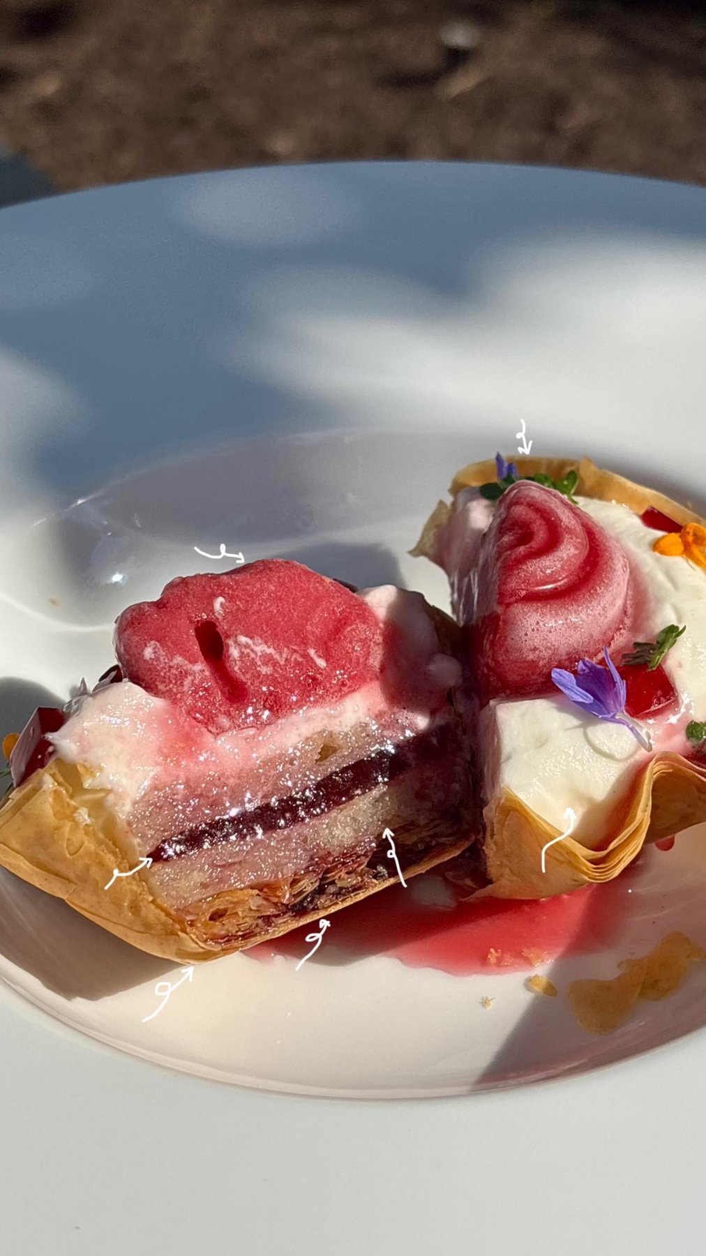 Berry phyllo cups with cream and edible flowers on a white plate